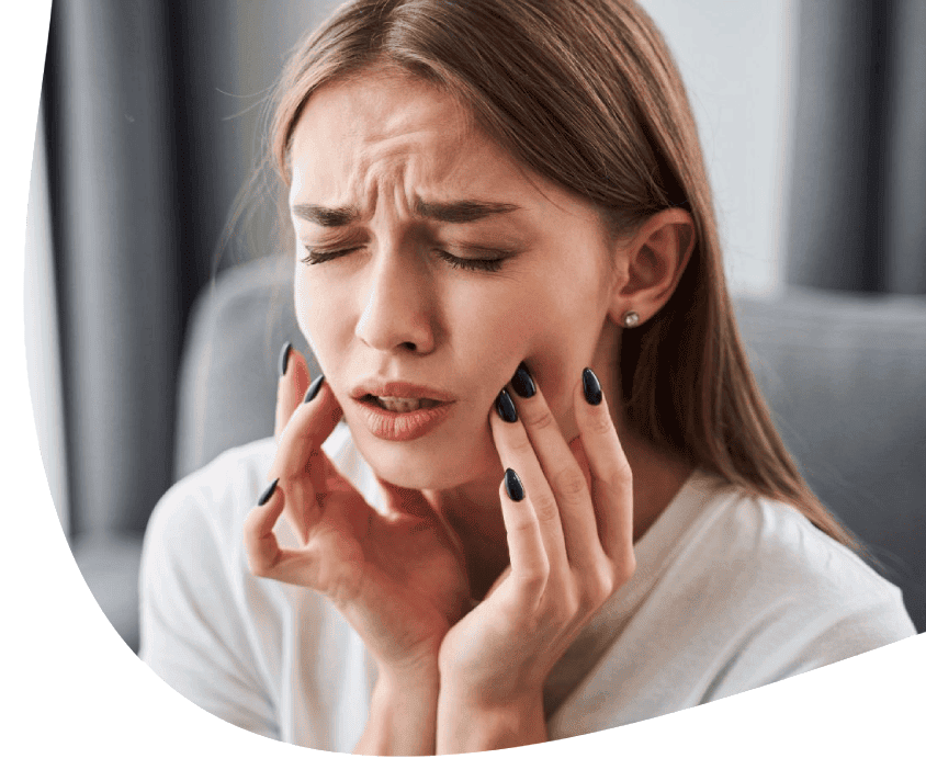 Žena, která se dotýká obou tváří, ve tváři má bolestný výraz.