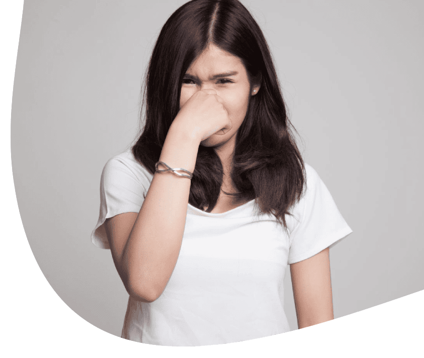 Mladá žena si zakrývá nos rukou, výraz obličeje naznačující nepříjemný zápach.