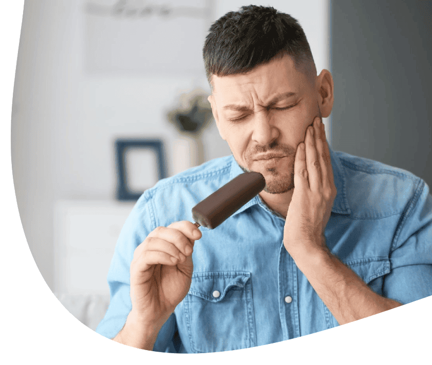 Muž si drží led na tváři, známky bolesti zubů po konzumaci zmrzliny.