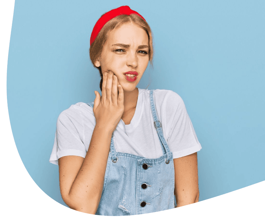 Mladá žena se s nepříjemnými pocity dotýká tváře a zdá se, že má bolesti zubů nebo čelistí.